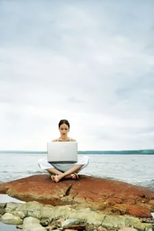 Woman working as Disney Specialist Woman sitting on the beach with a laptop wondering how to become a Disney travel agent